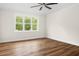 Cozy bedroom with hardwood floors, white trim, neutral walls, and a large window with a view of the backyard at 225 Whistlers Cv, Louisburg, NC 27549