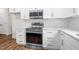 Well-lit kitchen features stainless steel appliances, white cabinets, and hardwood flooring for a sleek, modern style at 225 Whistlers Cv, Louisburg, NC 27549