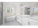 Bright main bathroom with double vanity, soaking tub, large window, and contemporary fixtures at 225 Whistlers Cv, Louisburg, NC 27549