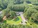 Aerial view of the house, detached garage, long driveway, and manicured green lawn surrounded by trees at 255 Morris Rd, Pittsboro, NC 27312