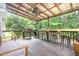 Covered back porch with ceiling fan, grill, outdoor seating, and views of the wooded lot at 255 Morris Rd, Pittsboro, NC 27312