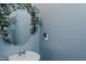 Charming powder room features blue walls and a decorative floral wreath around the mirror at 2586 Lacey Holt Rd, Graham, NC 27253