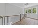 Upstairs hallway with hardwood floors, wood and metal railing, and large windows at 313 W Murray Ave, Durham, NC 27704