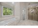 Bathroom featuring a soaking tub, walk-in shower, and marble style tiling at 3306 Meadowrun Dr, Durham, NC 27707