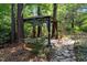 View of the backyard gazebo with curtains, stone walkway, and mature trees offering a quiet place to relax at 3306 Meadowrun Dr, Durham, NC 27707