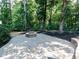 Backyard patio area featuring a fire pit and stone pavers, set amidst a wooded landscape at 354 Crimson Way, Pittsboro, NC 27312