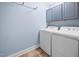 Functional laundry room with blue walls, tile floor, and new, white washer and dryer at 413 Braxman Ln, Holly Springs, NC 27540
