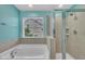 Bathroom showcases a tub and glass shower with tiled walls, and a large window for natural light at 428 Mill Station Ln, Wendell, NC 27591