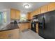 Cozy kitchen with maple cabinets, gray countertops, black appliances, and gray tiled backsplash at 4600 Landover Dale Dr, Raleigh, NC 27616