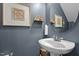 Stylish powder room featuring a round mirror, pedestal sink, and decorative wall art at 4600 Landover Dale Dr, Raleigh, NC 27616