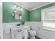 Green-toned bathroom with vanity, toilet, mirror, and window offering natural light at 4880 Old Us Hwy 64, Zebulon, NC 27597