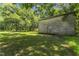 Side shot of a weathered wooden outbuilding surrounded by mature shade trees at 4880 Old Us Hwy 64, Zebulon, NC 27597