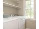Bright laundry room featuring a window, shelving, washer and dryer set at 505 Commander Dr, Wendell, NC 27591