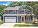 Charming two-story home with a blue exterior, red door, white trim, and an attached two car garage at 605 Catlin Rd, Cary, NC 27519