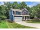 Charming two-story home with a blue exterior, red door, white trim, a long driveway, and a green lawn at 605 Catlin Rd, Cary, NC 27519