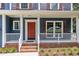 Close-up of a charming covered front porch with white railings, a red door, and manicured landscaping at 605 Catlin Rd, Cary, NC 27519