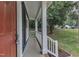 Side view of a charming covered front porch with white railings, a red door, and landscaped yard at 605 Catlin Rd, Cary, NC 27519