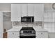 Close-up of cooktop, white cabinetry, stainless steel microwave, and mosaic backsplash at 605 Catlin Rd, Cary, NC 27519