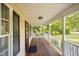 View of covered front porch with wood decking, white railing, and view of manicured front yard at 609 N Country Club Dr, Oxford, NC 27565