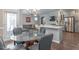 Open dining area features a glass table, gray chairs, hardwood floors, and an elegant chandelier at 6612 Enrichment Ln, Raleigh, NC 27616