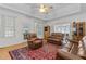 Bright living room with a ceiling fan, and large windows, showcasing leather furniture, and a patterned rug at 9 Piney Grove Rd, Bahama, NC 27503