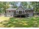 A large backyard features a light gray house with a deck and lush, green trees at 908 Snow Hill Rd, Durham, NC 27712