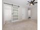 Bright bedroom featuring carpeted floors, ceiling fan, and barn door entry to the bathroom at 908 Snow Hill Rd, Durham, NC 27712