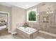 Spa-like bathroom features a soaking tub with a large window and a separate shower with a bench at 908 Woodland Grove Way, Wake Forest, NC 27587