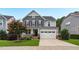 Beautiful two-story home with gray siding, stone accents, a covered porch, and a well-manicured front yard and 2-car garage at 908 Woodland Grove Way, Wake Forest, NC 27587