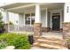 Inviting front porch with stone pillars, a seating area, decorative plants and a welcoming entrance with stylish door at 908 Woodland Grove Way, Wake Forest, NC 27587