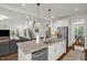Kitchen island with stone countertops, stainless steel appliances, and seating, flowing into living area at 908 Woodland Grove Way, Wake Forest, NC 27587