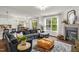 Spacious living area with a large sectional sofa, a fireplace, hardwood floors, and expansive windows that flood the room with natural light at 908 Woodland Grove Way, Wake Forest, NC 27587