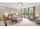 Serene main bedroom featuring tray ceilings, neutral colors, bench, cozy furniture, and abundant natural light at 908 Woodland Grove Way, Wake Forest, NC 27587