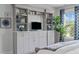 Bright bedroom features custom built-ins, drawers, shelves, TV, and a large plant near a window at 909 Green Oaks Pkwy, Holly Springs, NC 27540