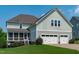 Rear exterior showcasing the house, three-car garage, screened porch, and manicured lawn at 909 Green Oaks Pkwy, Holly Springs, NC 27540