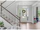 Bright foyer features wood floors, a staircase, and a glass front door with a wreath at 909 Green Oaks Pkwy, Holly Springs, NC 27540