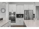 Bright kitchen with stainless steel appliances and stacked ovens surrounded by white cabinets at 909 Green Oaks Pkwy, Holly Springs, NC 27540