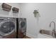Functional laundry room featuring modern washer and dryer units, sink, and storage shelving at 909 Green Oaks Pkwy, Holly Springs, NC 27540
