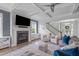 Open living room with hardwood floors, a fireplace, comfortable seating, and stairs to the second floor at 909 Green Oaks Pkwy, Holly Springs, NC 27540