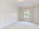 A well-lit bedroom features wainscotting, neutral paint, carpet, and a window at 102 Bosswood Ct, Cary, NC 27518