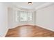 Bright bedroom featuring a trey ceiling, a large window area with plantation shutters, and hardwood floors at 102 Bosswood Ct, Cary, NC 27518