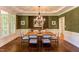 Elegant dining room with stylish chandelier, dark green accent wall, and wainscoting at 102 Bosswood Ct, Cary, NC 27518