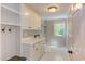 A well-lit laundry room with bright white cabinetry, sink, and coat hooks at 102 Bosswood Ct, Cary, NC 27518