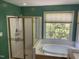 Bright bathroom featuring a shower, soaking tub, and window looking into the backyard at 104 Belle Isle Ct, Cary, NC 27513