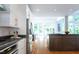 A sunlit kitchen features stainless steel appliances, white cabinets, granite countertops, an island, and hardwood floors at 105 Woodsage Way, Cary, NC 27518