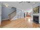 Open-concept living room with hardwood floors, fireplace, and staircase, seamlessly connected to the kitchen at 111 Finsbury St, Durham, NC 27703
