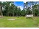 Expansive backyard with lush green grass, tall trees, and a white storage shed, perfect for outdoor activities and storage at 132 Ironwood Ln, Clayton, NC 27520
