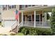 Charming front porch with a welcoming American flag, surrounded by vibrant plants and a cozy seating area at 1713 Mclaurin Ln, Fuquay Varina, NC 27526