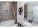 Bathroom with gray tile, white bathtub, granite vanity, and decorative art at 189 Churchill Way, Clayton, NC 27520