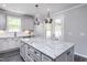Stylish kitchen featuring a granite island, white cabinets, modern appliances, and contemporary lighting at 189 Churchill Way, Clayton, NC 27520